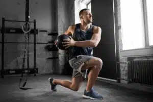 Man using a weighted exercise ball to perform a "weighted lunge and twist"