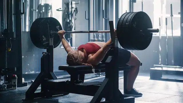 Woman performing a bench press with an arch in her back for increased stability and power