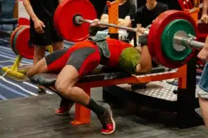 Man performing a heavy bench press during a powerlifting competition