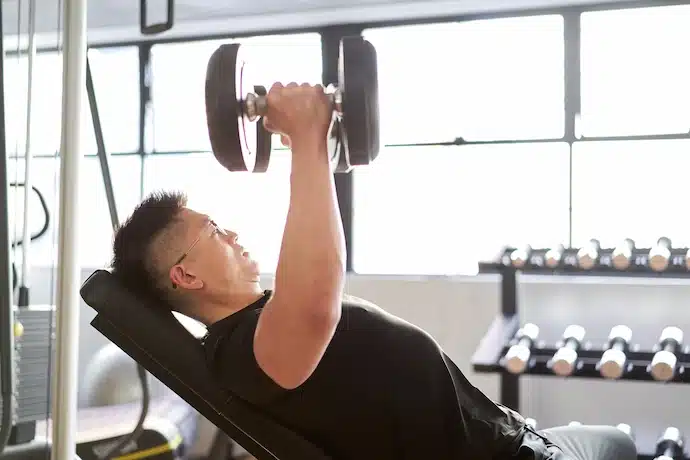 Incline dumbbell fly exercise being performed by a man