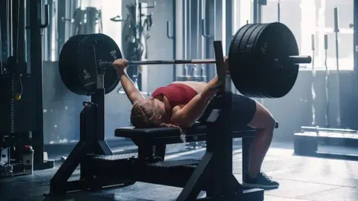 Woman performing a bench press with an arch in her back for increased stability and power